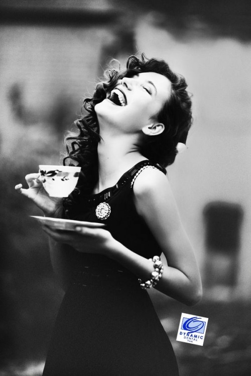 woman laughs while holding cup and saucer