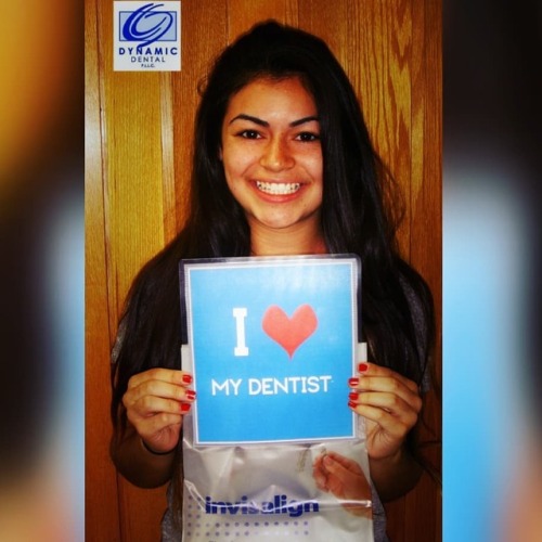 smiling woman holds sign saying "I Love My Dentist"